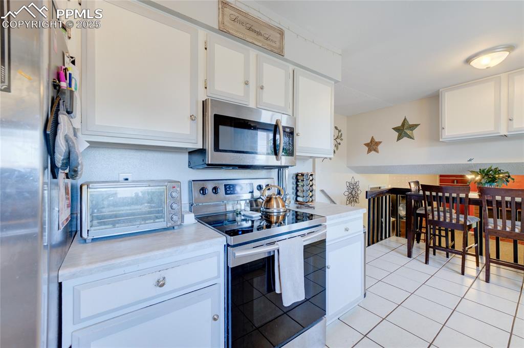 Image 14 of 35: Kitchen with appliances with stainless steel finishes, light countertops, w
