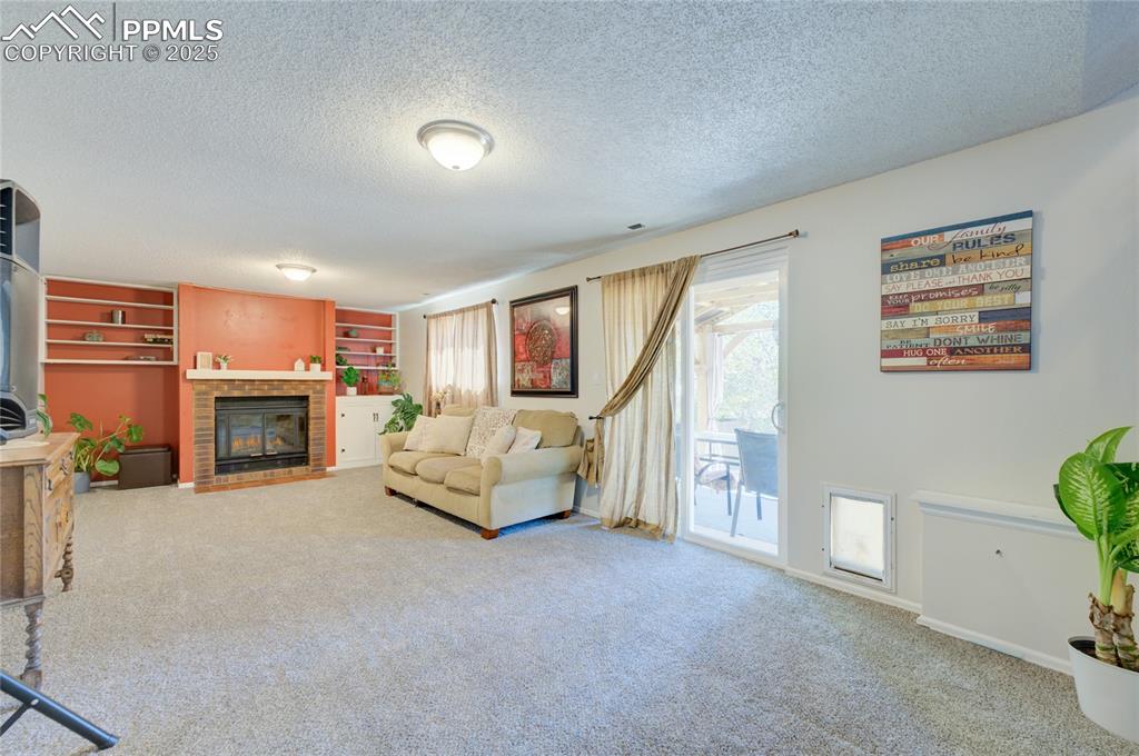 Image 24 of 35: Carpeted living area featuring a textured ceiling, built in features, and a