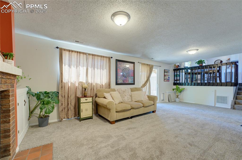 Image 28 of 35: Living room with carpet floors, a textured ceiling, and a fireplace