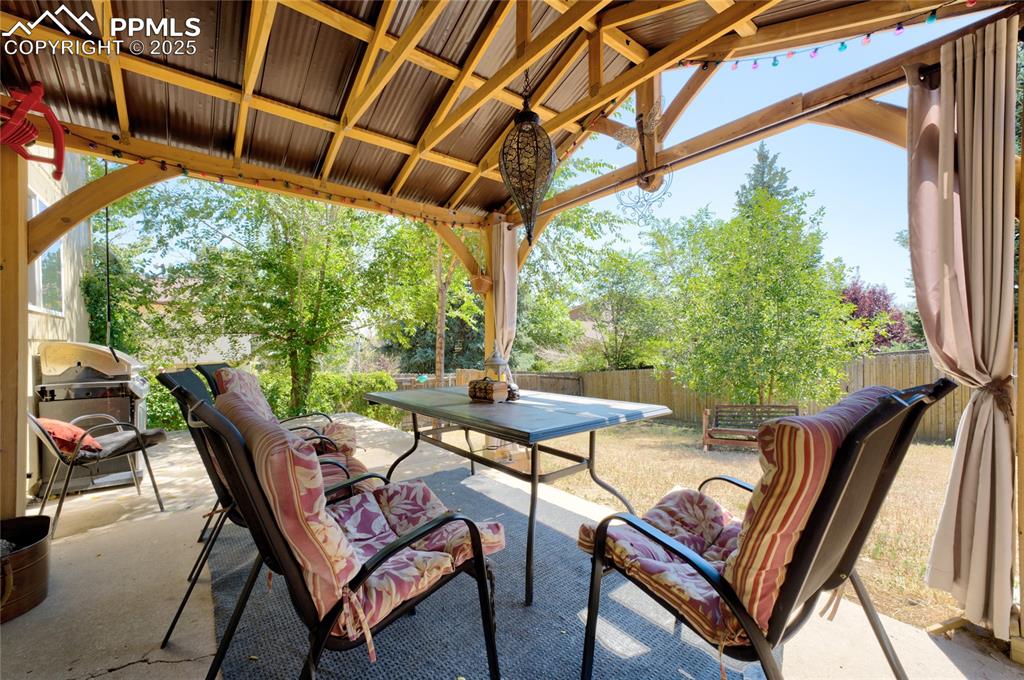 Image 31 of 35: Fenced backyard with a patio, outdoor dining space, and grilling area