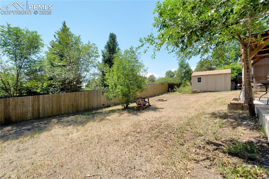 Image 32 of 35: Fenced backyard featuring a shed
