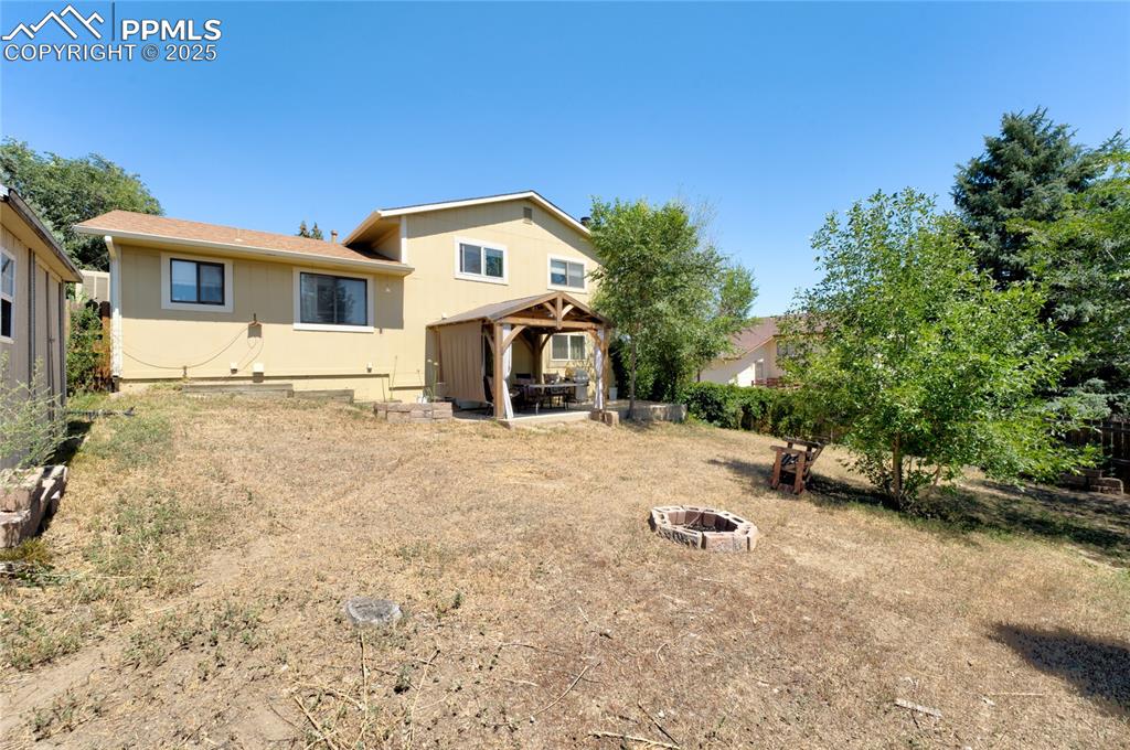 Image 34 of 35: Back of property featuring a patio, a fire pit, and a gazebo