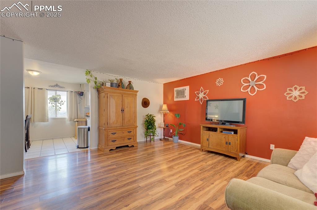 Image 5 of 35: Living room featuring a textured ceiling and light wood-type flooring