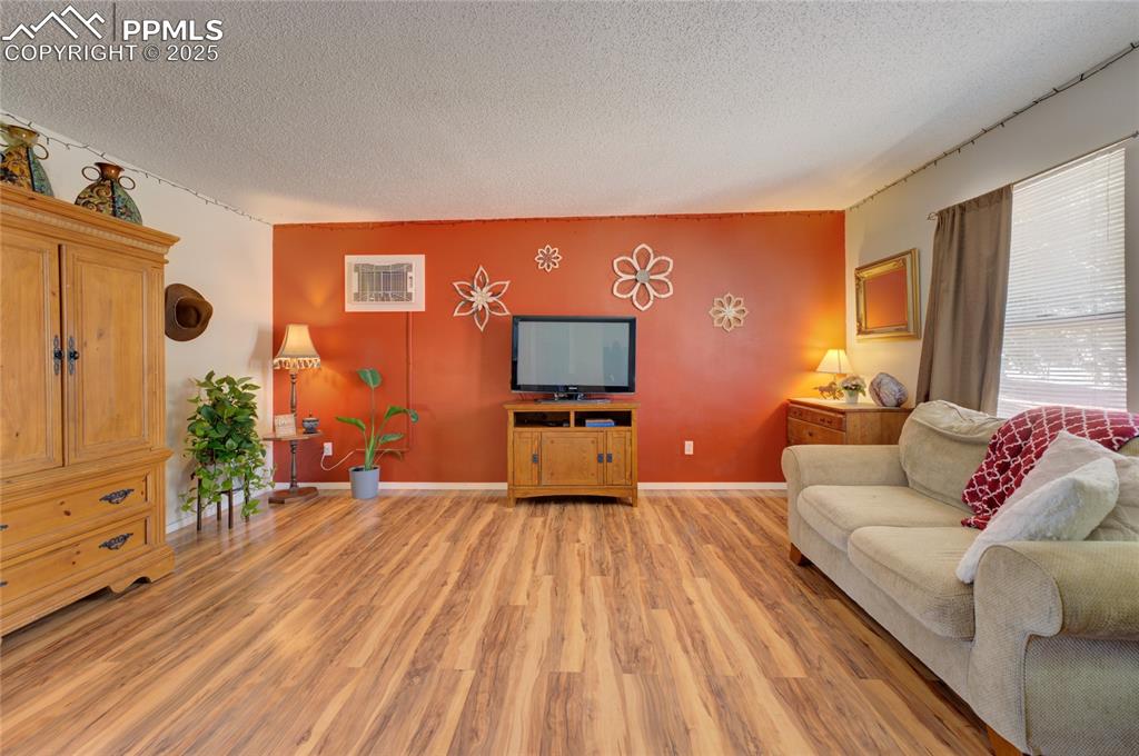 Image 6 of 35: Living area featuring a textured ceiling and light wood-style floors