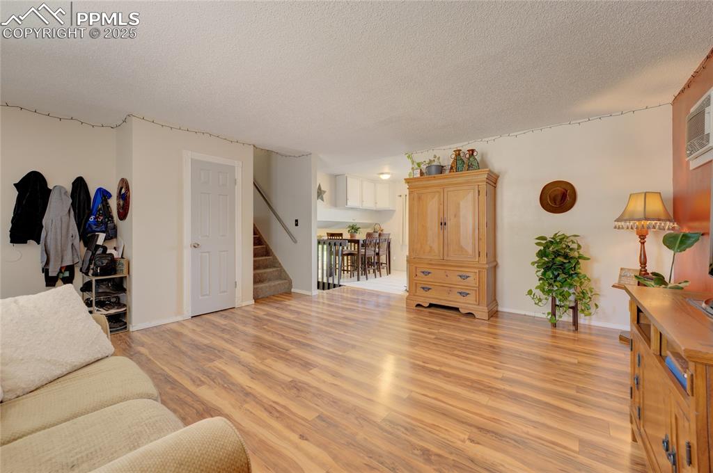 Image 8 of 35: Living area featuring light wood-style floors, a textured ceiling, stairs,