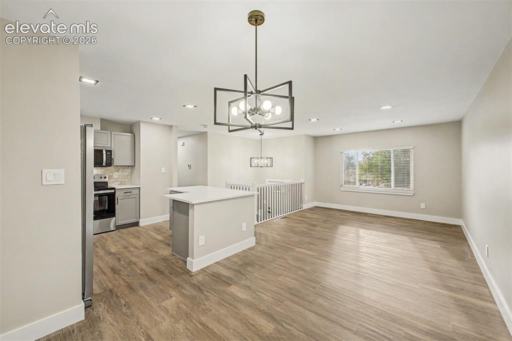 Image 10 of 36: Open-concept area featuring wood-finish flooring, a kitchen island with a l