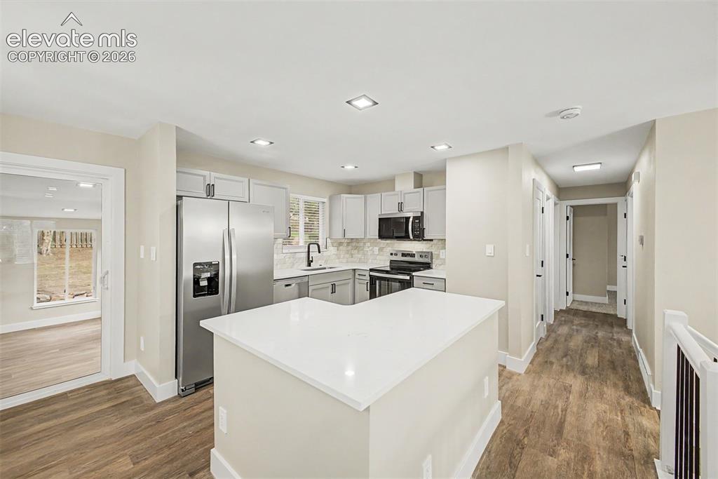 Image 11 of 36: Kitchen featuring an island with a white countertop, stainless steel applia