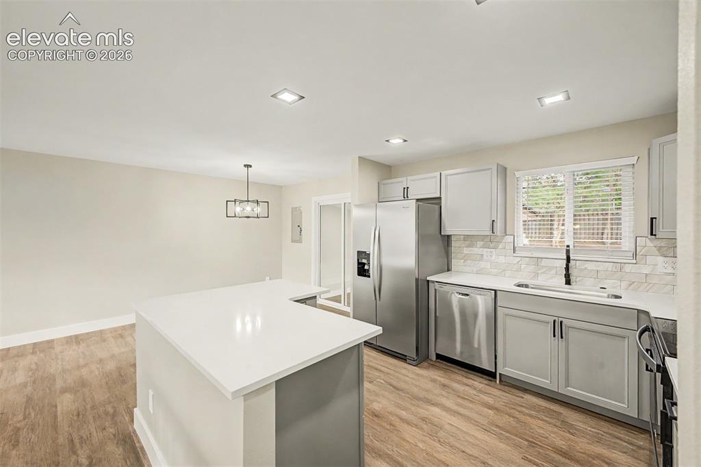 Image 13 of 36: Contemporary kitchen featuring a peninsula island with a light-toned counte