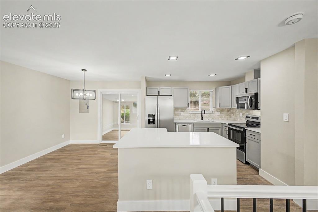 Image 15 of 36: Open concept kitchen featuring light grey cabinetry, stainless steel applia