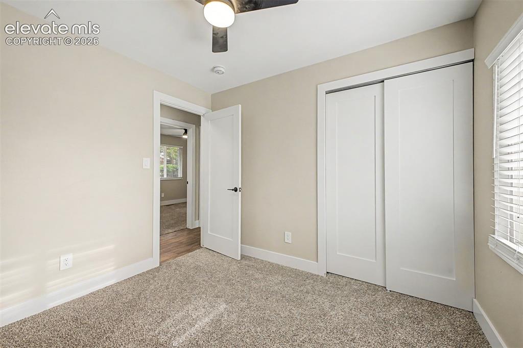 Image 22 of 36: Plush carpet flooring, a ceiling fan with integrated lighting, window blind