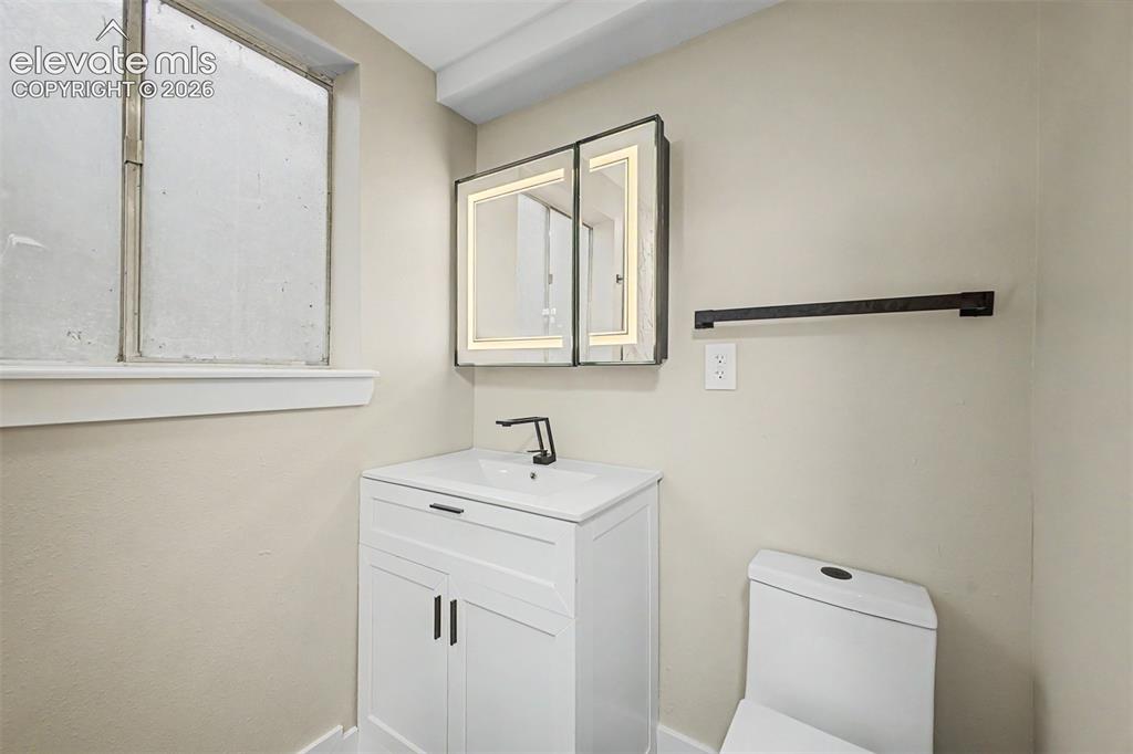 Image 23 of 36: White vanity with an integrated sink, matte black faucet, and matching cabi
