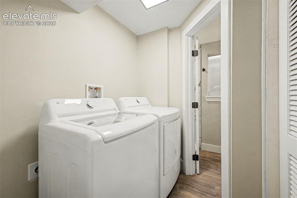 Image 27 of 36: Laundry area featuring wood-finish flooring and a white louvered door