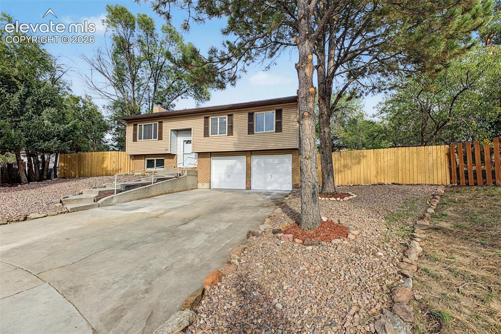 Image 28 of 36: Split-level residence featuring a two-car garage, concrete driveway, and a