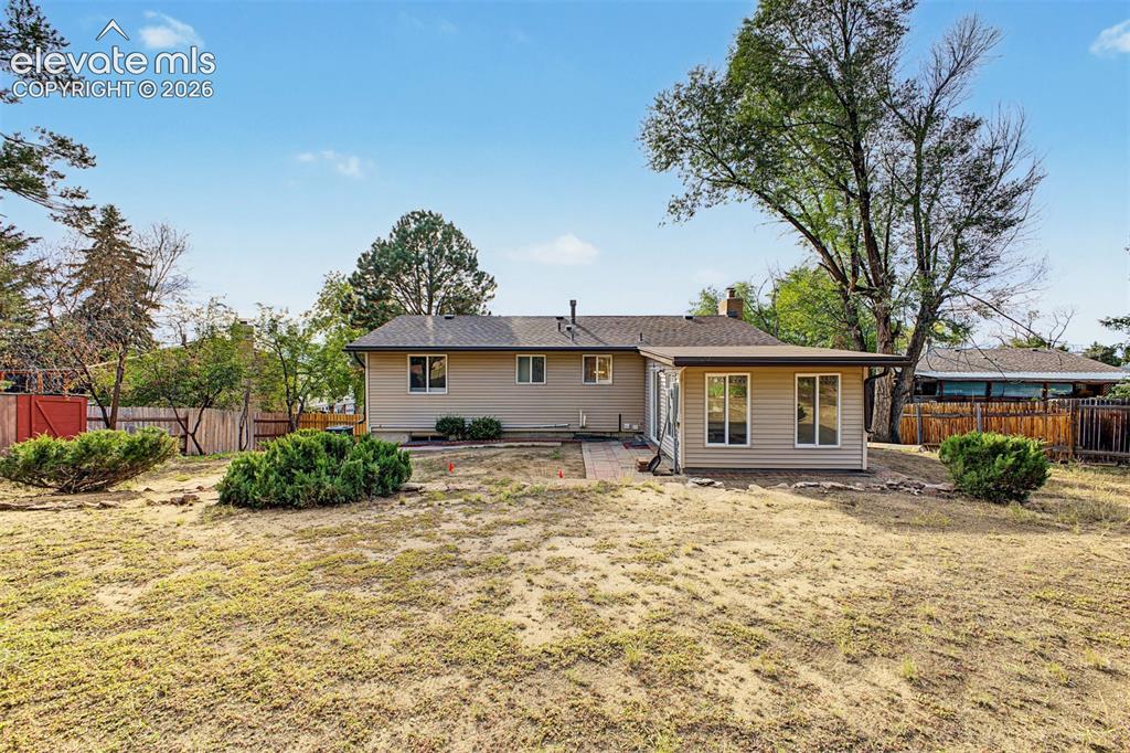 Image 32 of 36: Expansive backyard featuring a partial privacy fence and mature trees