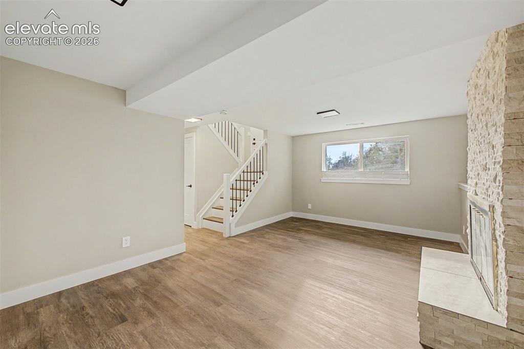 Image 5 of 36: Expansive room featuring wood-finish flooring, a stone-clad fireplace with 