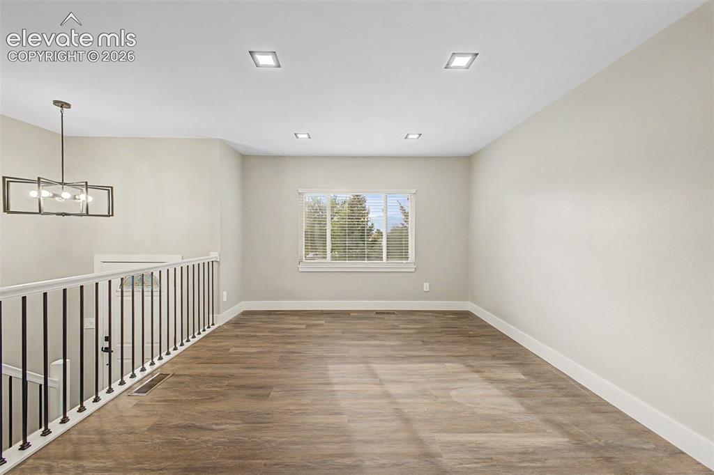 Image 7 of 36: Wood-finish flooring, recessed lighting, contemporary chandelier, white win