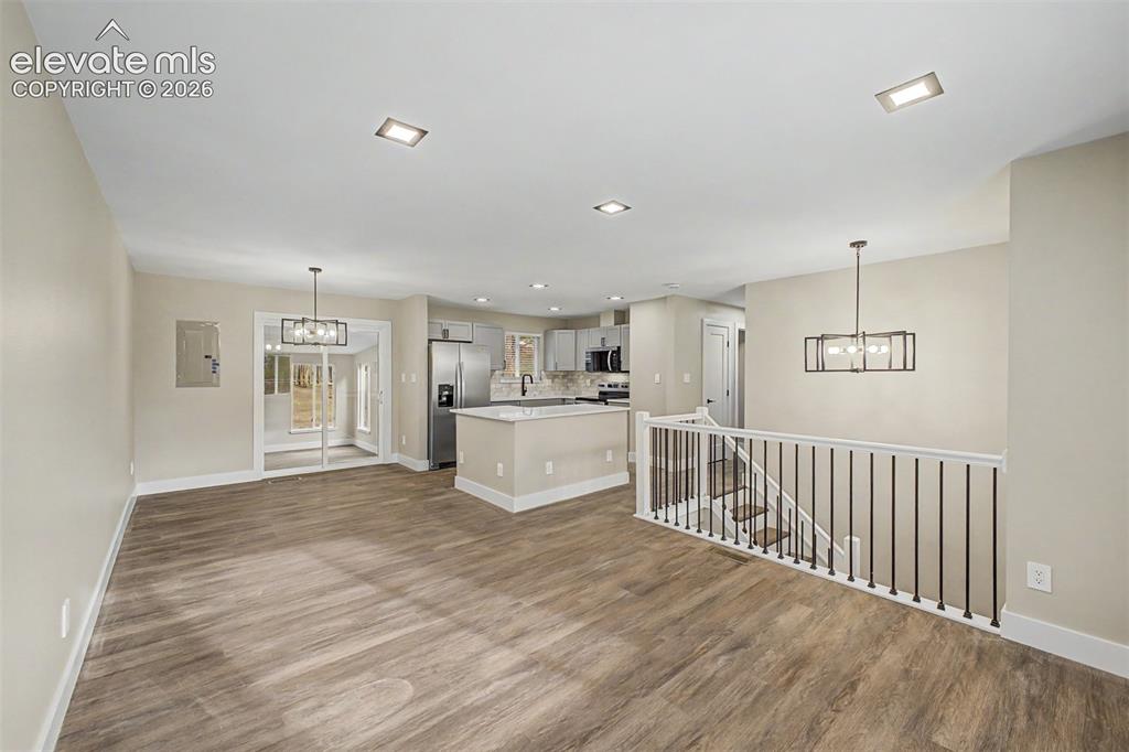 Image 8 of 36: Open-concept living area featuring wood-finish flooring, recessed lighting,