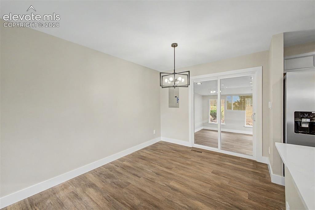 Image 9 of 36: Wood-finish flooring, contemporary chandelier, sliding glass door, neutral 