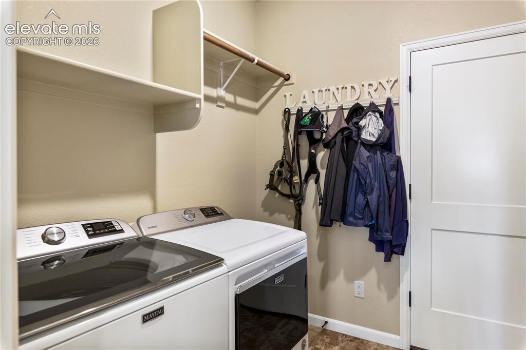 Image 29 of 39: Utility space featuring built-in overhead storage shelving, a wooden garmen