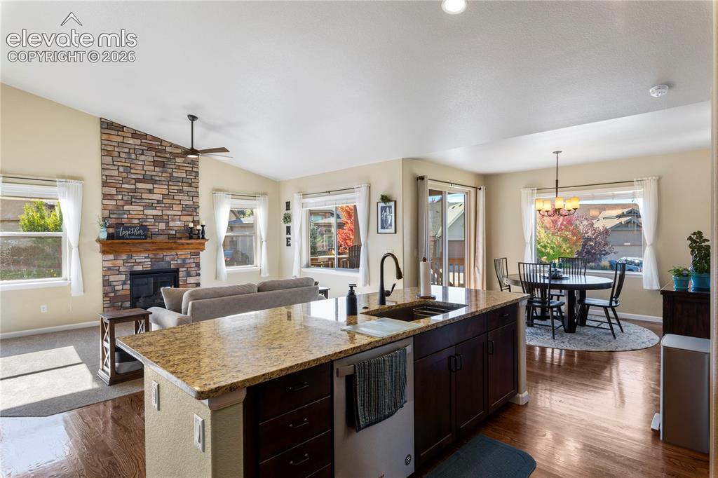 Image 7 of 39: Open-concept kitchen featuring an island with stone-finish countertops, dar