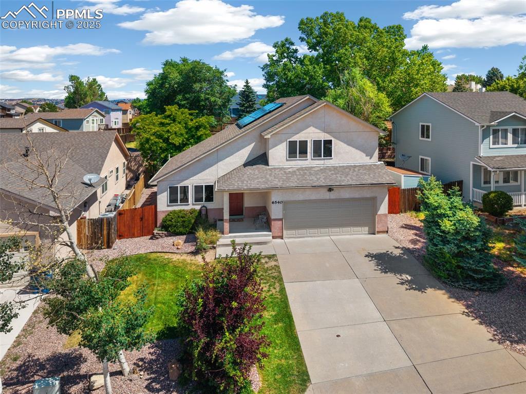 Caption: Traditional home featuring concrete driveway, solar panels, an attached garage, a residential view, 