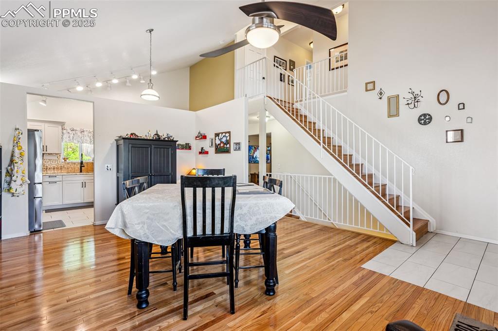 Image 11 of 32: Dining room with light wood-type flooring, stairs, ceiling fan, track light