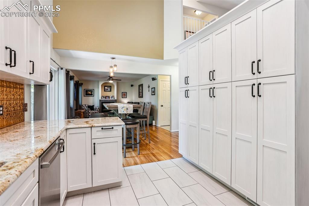 Image 12 of 32: Kitchen with ceiling fan, white cabinetry, dishwasher, a peninsula, and a t