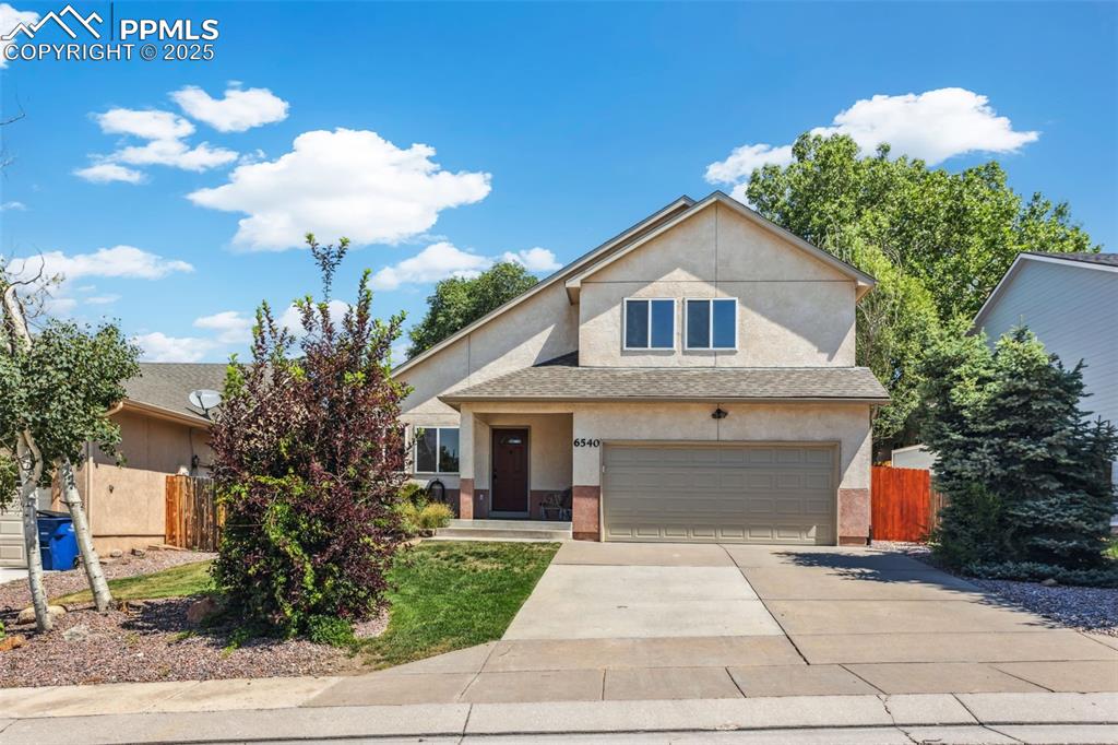 Image 5 of 32: View of front facade with stucco siding, concrete driveway, a garage, and r