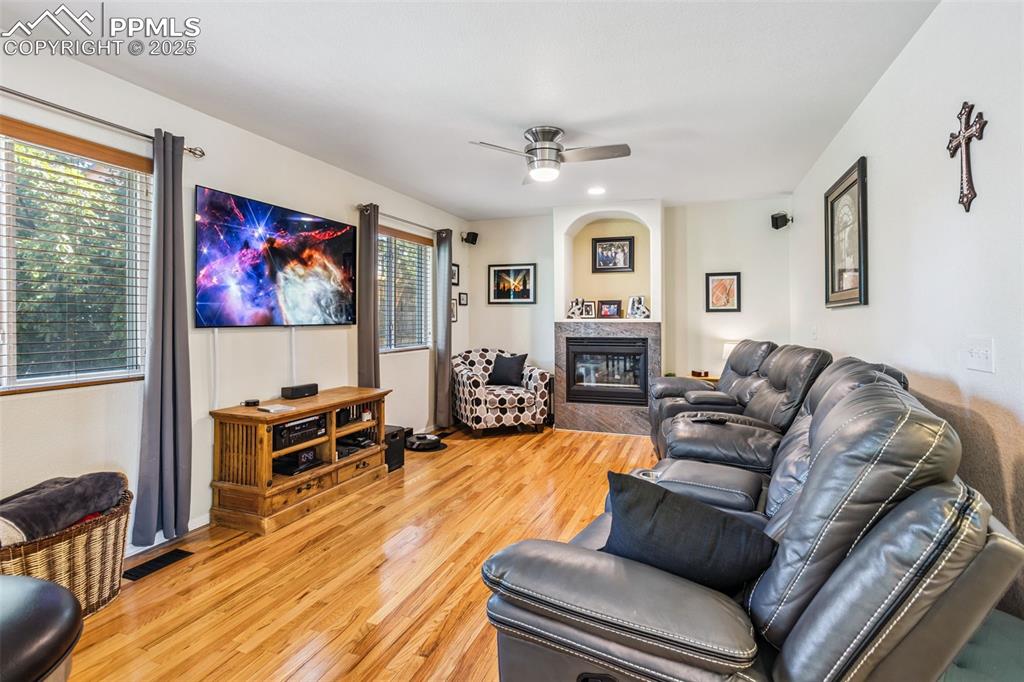 Image 7 of 32: Living area with ceiling fan, light wood-style floors, and a glass covered