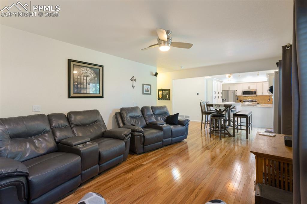 Image 8 of 32: Living room featuring light wood finished floors and a ceiling fan