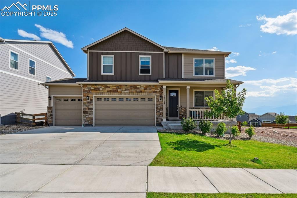 Caption: Craftsman house featuring a porch, stone siding, driveway, board and batten siding, and a front yard