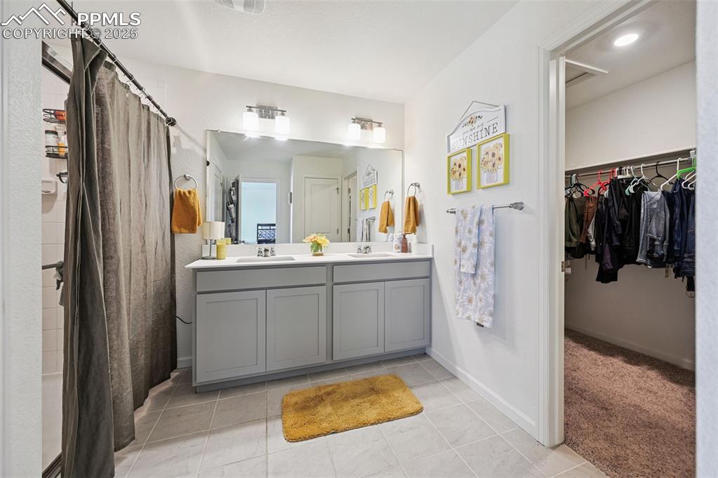 Image 18 of 32: Primary bath featuring double vanity, updated light fixtures, shower, and a