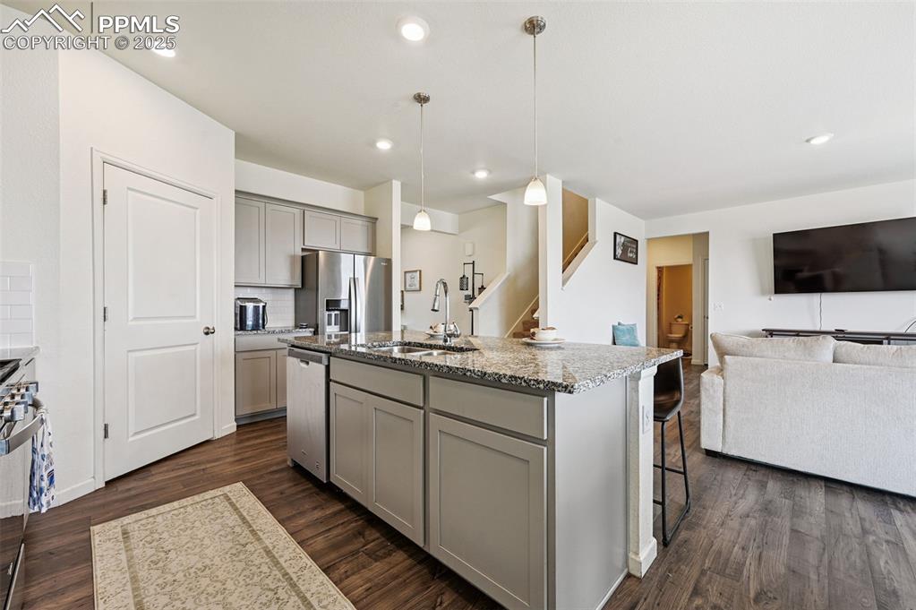 Image 7 of 32: Kitchen with gray cabinetry, Kitchen island featuring sink and dishwasher.
