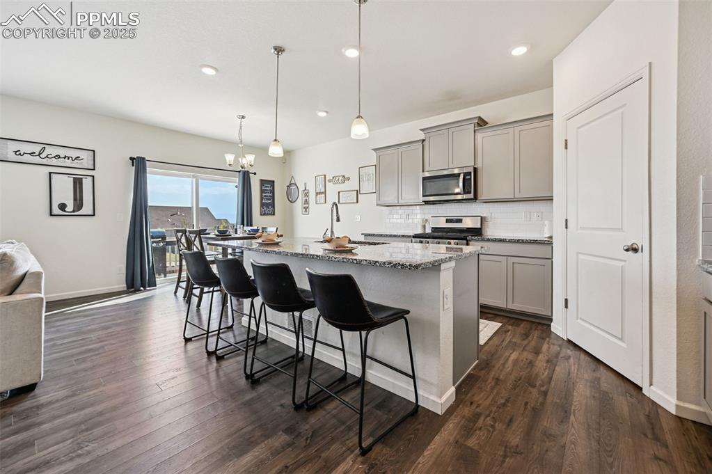 Image 8 of 32: Kitchen featuring gray cabinetry, light stone counters, a center island wit