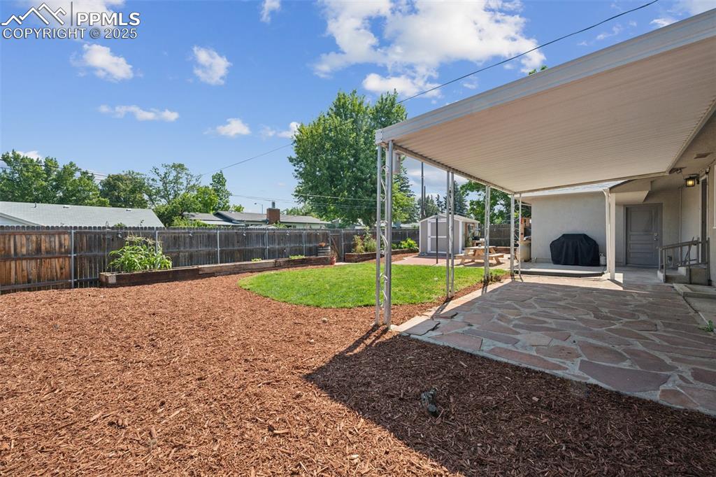 Image 26 of 30: Fenced backyard with a patio area and a storage shed