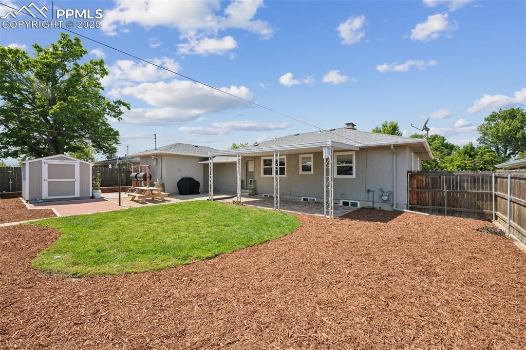 Image 28 of 30: Back of property featuring a patio area, a fenced backyard, a storage shed,
