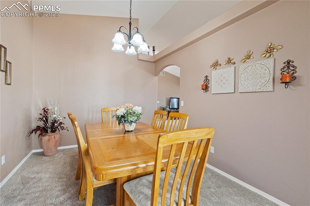 Image 19 of 41: Dining space with carpet floors, arched walkways, and a chandelier