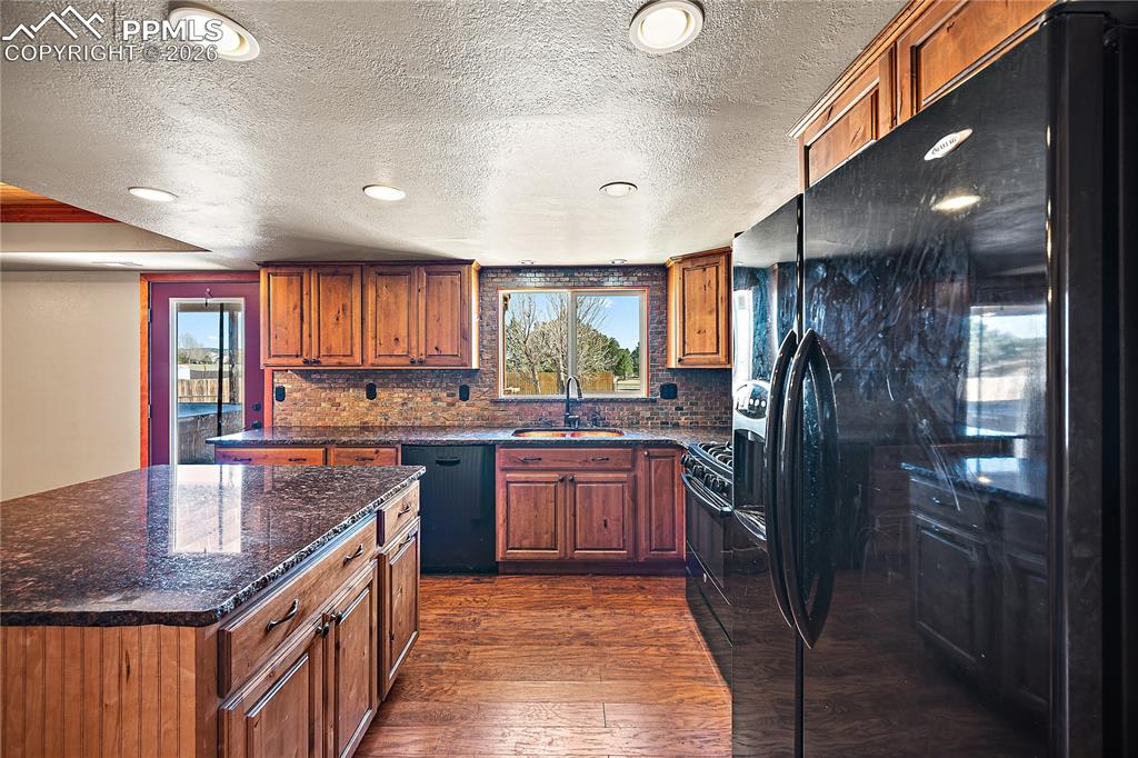 Image 10 of 40: Spacious kitchen with granite, large island, gas range and black appliances