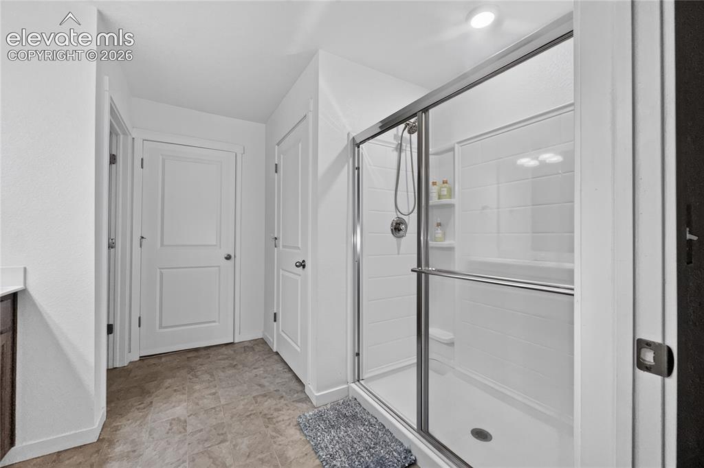 Image 11 of 22: Walk-in shower with clear glass enclosure and sliding door, white tile-patt