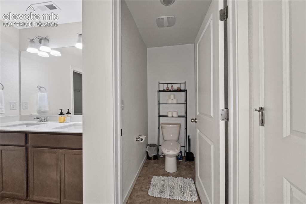 Image 12 of 22: Bathroom featuring a dual vanity with dark wood-finish cabinetry and a whit