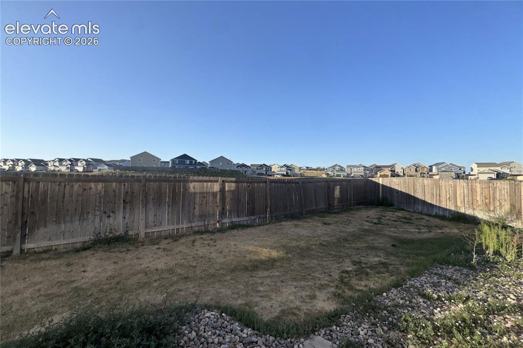 Image 18 of 22: Expansive backyard featuring a wood privacy fence, gravel border, and a bro