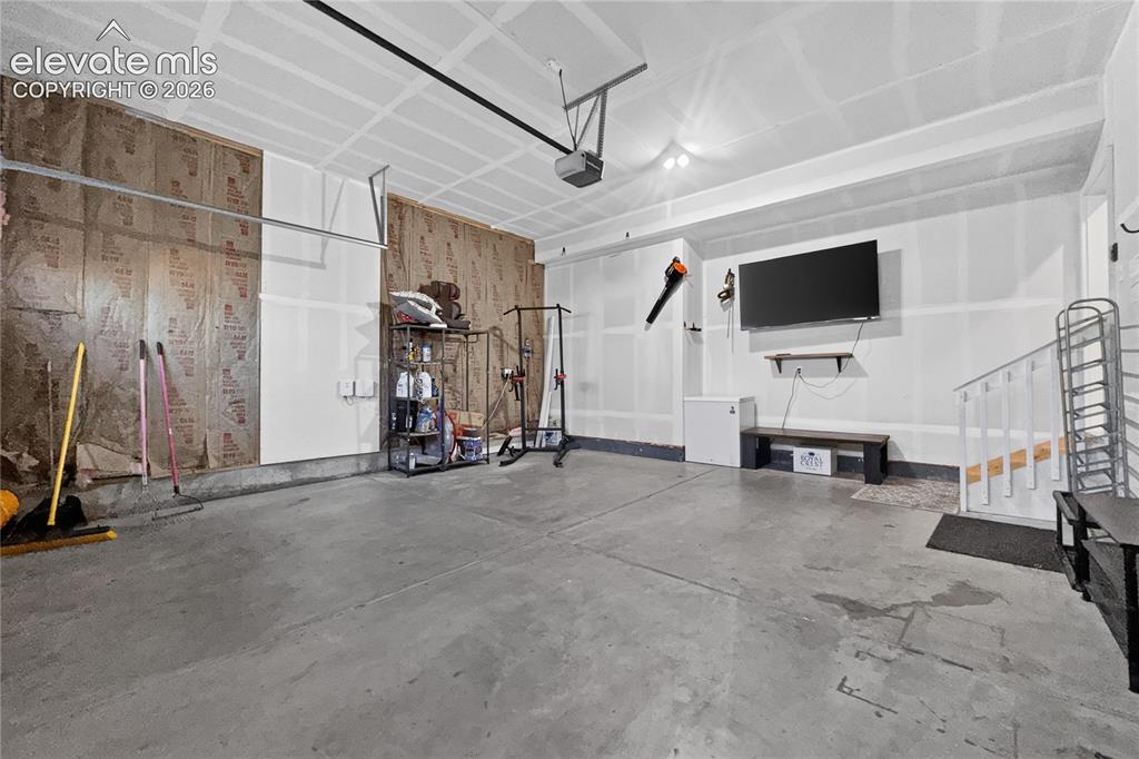 Image 19 of 22: Spacious garage featuring concrete flooring and exposed insulation