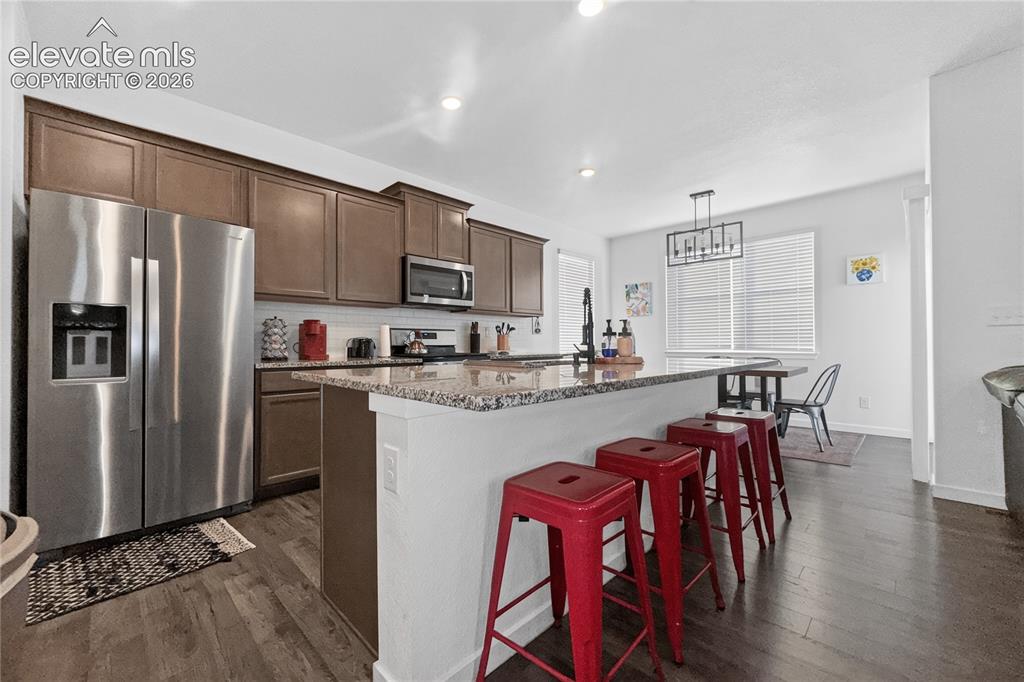 Image 3 of 22: Kitchen featuring wood-finish flooring, granite countertops, stainless stee
