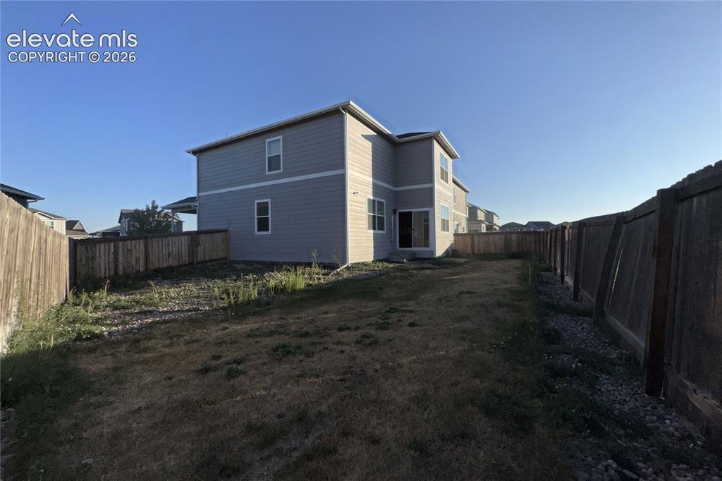 Image 4 of 22: Spacious backyard with a two-story residence featuring light gray siding