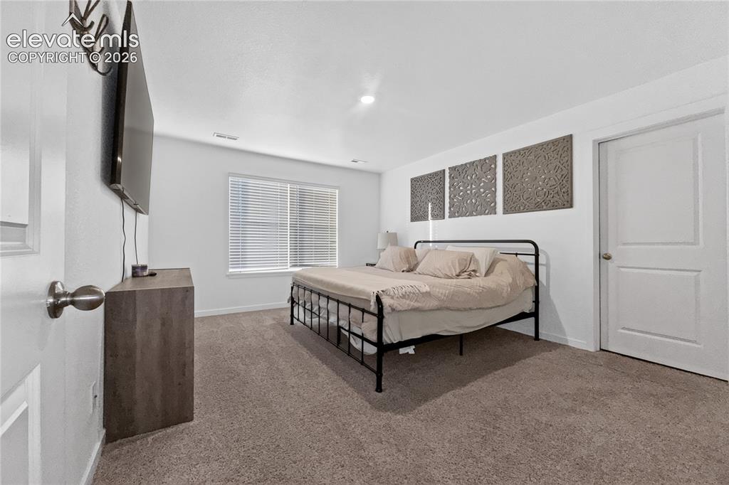 Image 8 of 22: Spacious room featuring neutral carpeting, a large window with horizontal b
