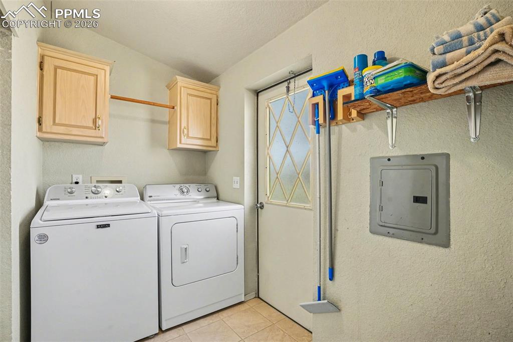 Image 19 of 27: Functional laundry room featuring cabinets, shelving, and direct access to 