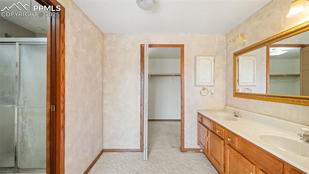 Image 17 of 36: Bathroom featuring a spacious closet, double vanity, and a shower stall