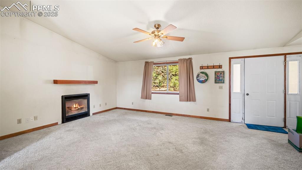 Image 5 of 36: Unfurnished living room with carpet, a glass covered fireplace, a ceiling f