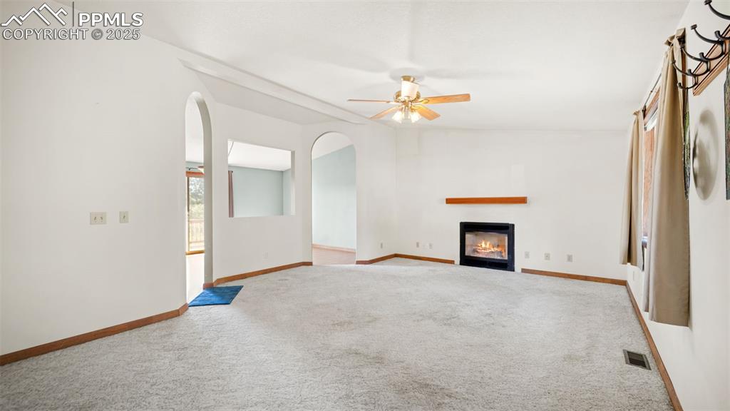 Image 6 of 36: Unfurnished living room featuring carpet floors, a glass covered fireplace,