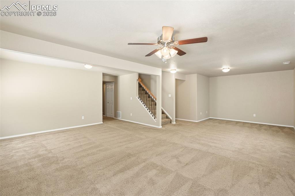 Image 27 of 44: Spacious family room with ceiling fan in basement.